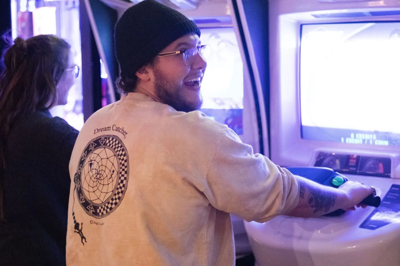 A guest in a toque laughing at an arcade cabinet