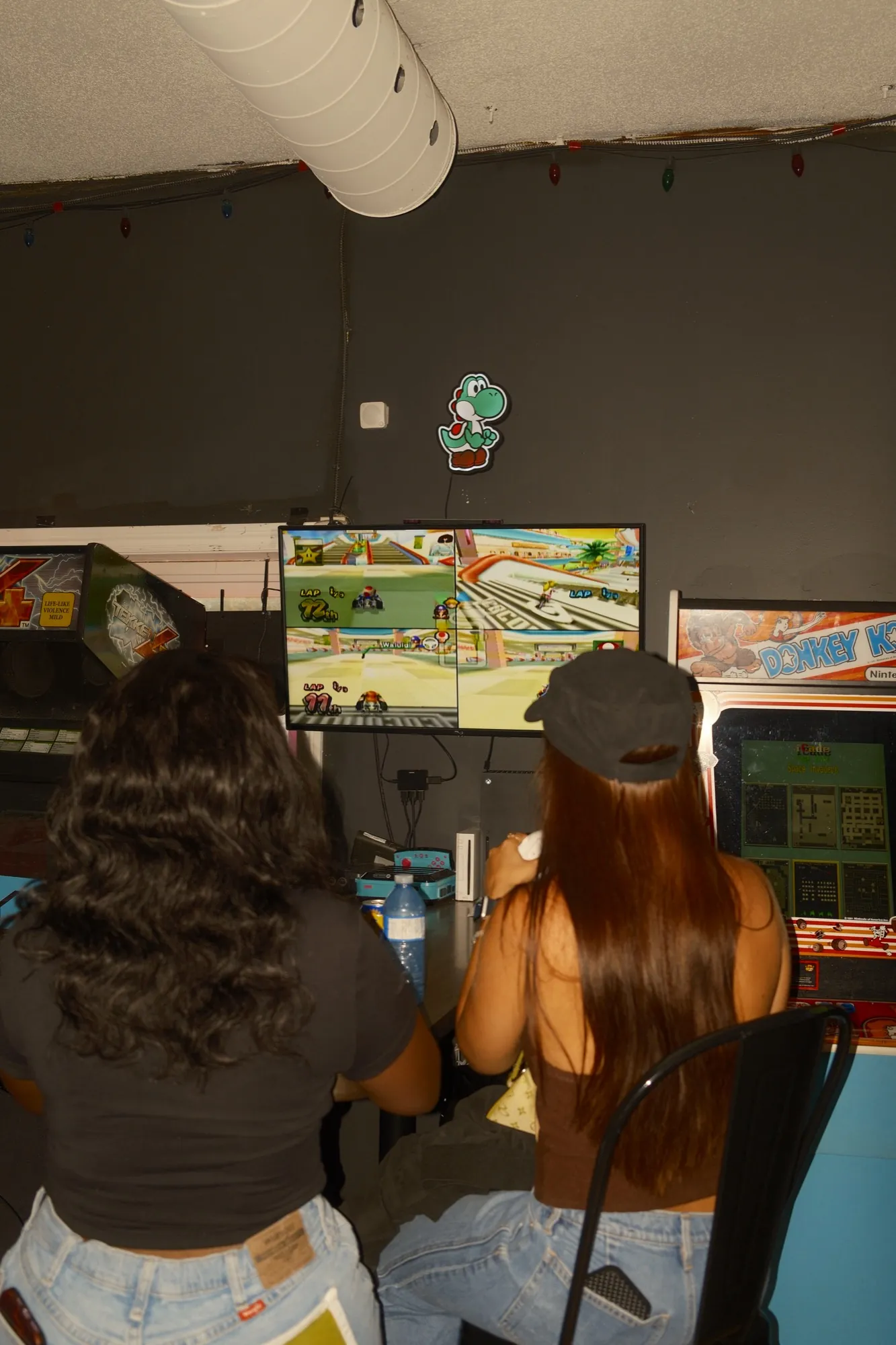 Two people playing side by side at arcade cabinets