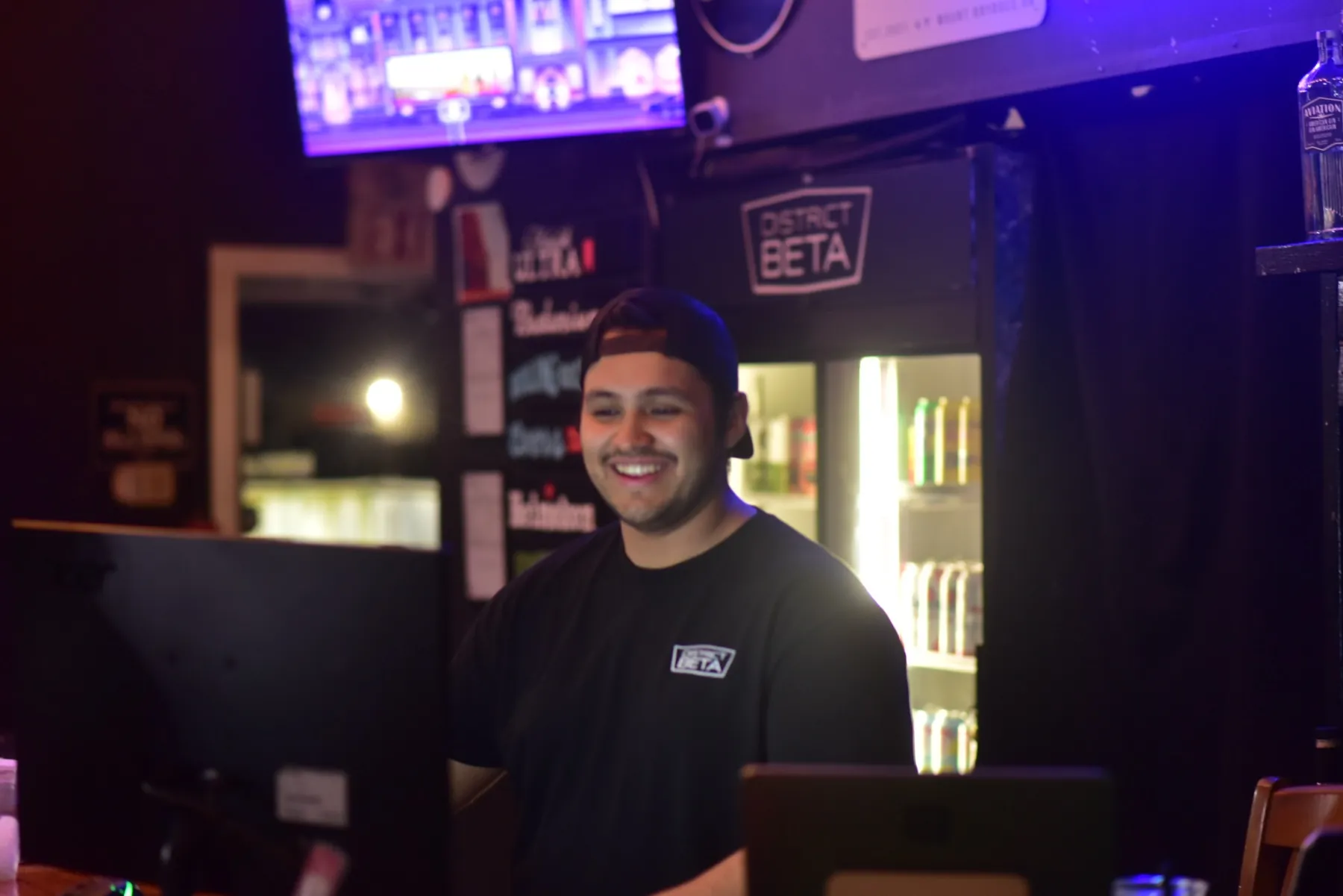 A smiling staff member at the District Beta front counter