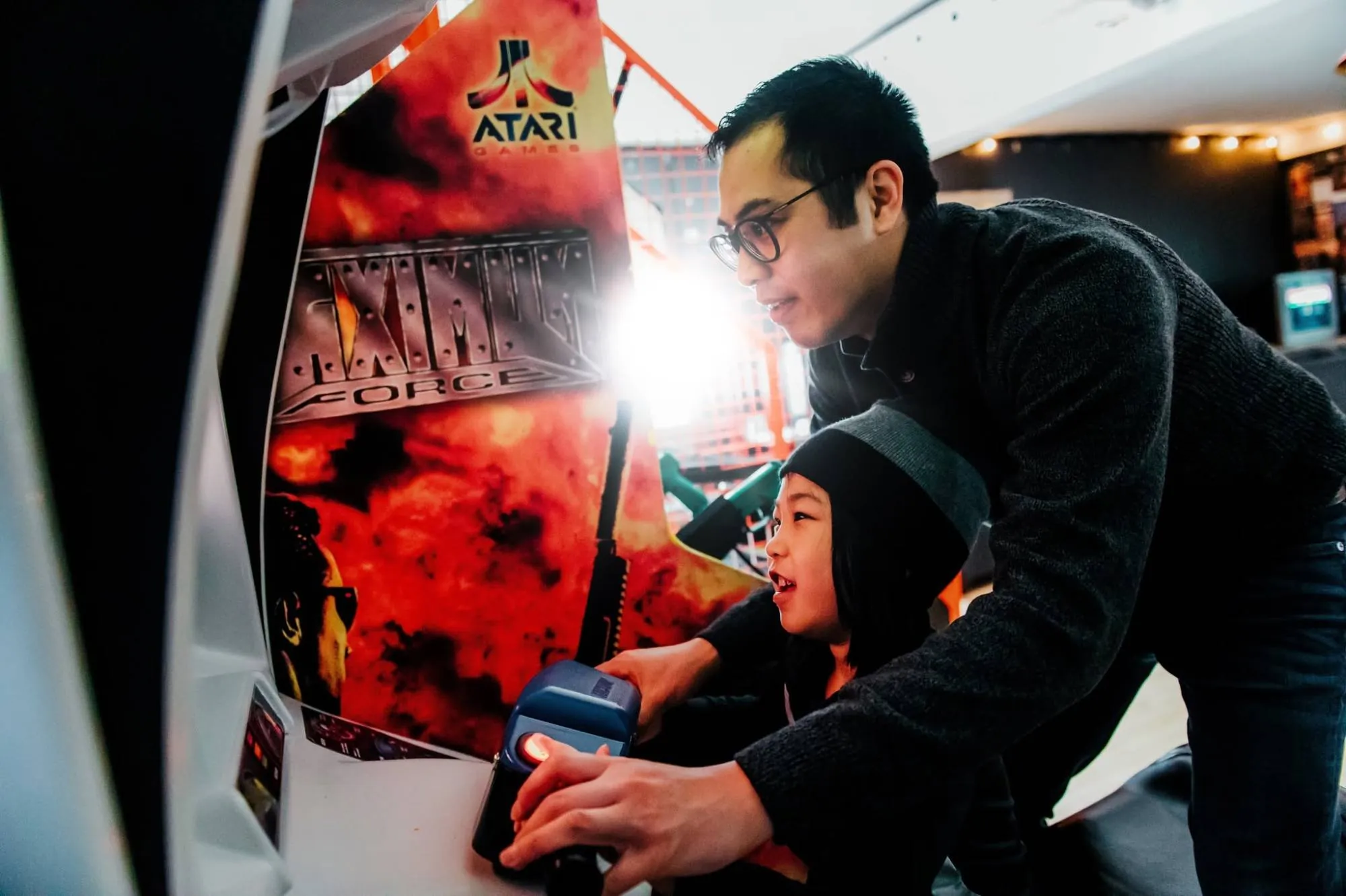 A dad and a kid aiming light guns at an arcade cabinet