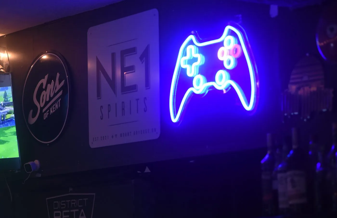 A neon game controller sign on the wall